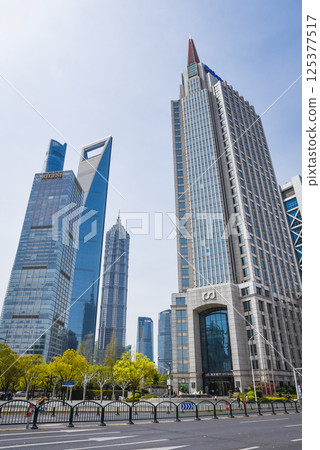 The Shanghai World Financial Center stands tall among Pudongs skyscrapers, its distinctive trapezoid aperture piercing the clear daylight sky. 125377517