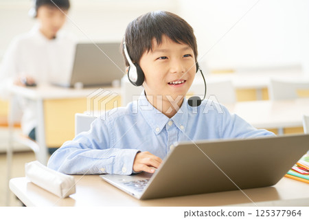 Elementary school students learning with headsets | Hybrid lessons connecting online and classrooms 125377964