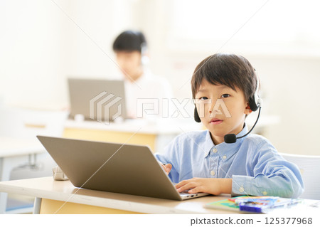 Elementary school students learning with headsets | Hybrid lessons connecting online and classrooms Elementary school students learning with headsets | Hybrid lessons connecting online and classrooms 125377968