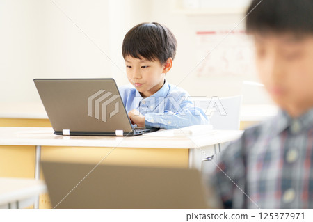 Elementary school boy staring at a laptop screen 125377971