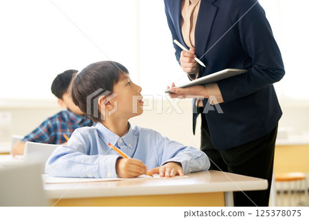 Elementary school boy learning from his teacher Elementary school boy learning from his teacher 125378075