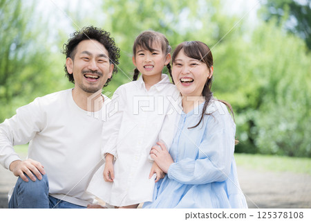 Close-up portrait of a smiling family of three looking at the camera in fresh greenery Close-up portrait of a smiling family of three looking at the camera in fresh greenery 125378108