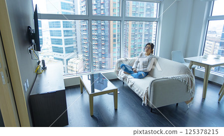 woman wear glasses sit on the sofa and feel stressed, full body shot with house estate background woman wear glasses sit on the sofa and feel stressed, full body shot with house estate background 125378215