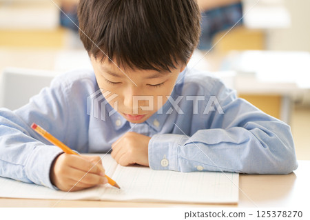 Elementary school boy concentrating and taking notes Elementary school boy concentrating and taking notes 125378270