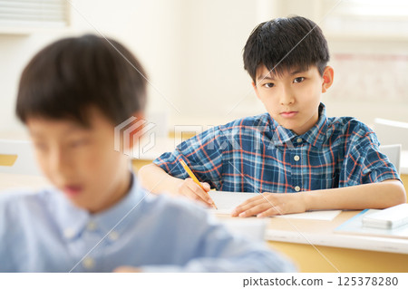 A male elementary school student looking ahead with a serious expression A male elementary school student looking ahead with a serious expression 125378280