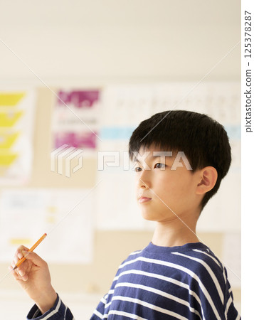 Elementary school student thinking with a pencil in hand 125378287