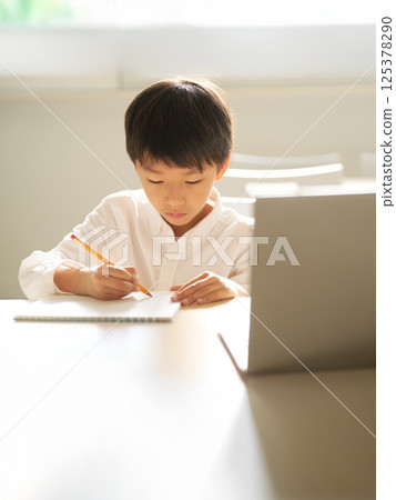 Elementary school boy writing in notebook Elementary school boy writing in notebook 125378290