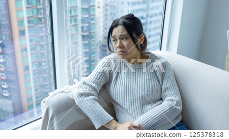woman wear glasses sit on the sofa and feel stressed, full body shot with house estate background 125378318
