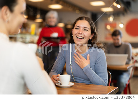 Girl in cafe sits opposite female companion, has nice conversation 125378804