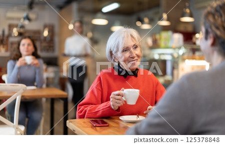 Elderly woman meets a man in a cafe. Conversation over cup of coffee 125378848