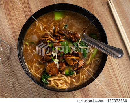 Beef soup with noodles and vegetables on a wooden background Beef soup with noodles and vegetables on a wooden background 125378888