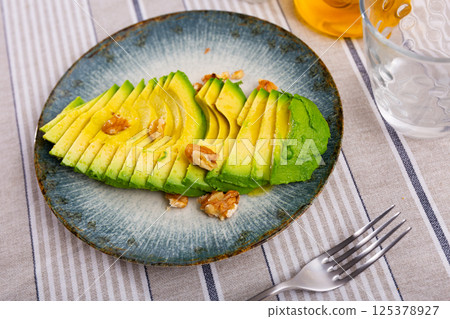 Appetizing avocado and walnuts at table Appetizing avocado and walnuts at table 125378927