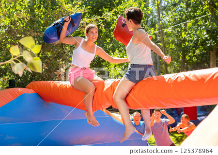 Women holding soft pillows and fighting in adventure park 125378964