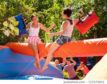 Women holding soft pillows and fighting in adventure park Women holding soft pillows and fighting in adventure park 125379042