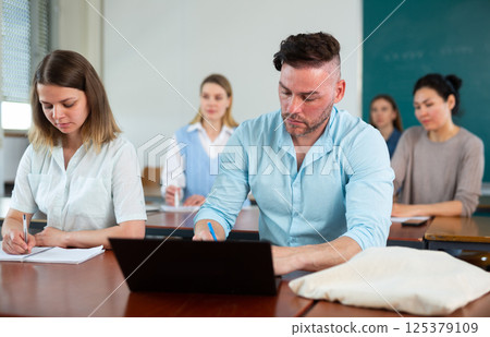 Students sitting at table during lesson 125379109