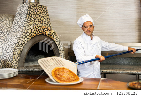 Skilled man chef preparing pizza in restaurant Skilled man chef preparing pizza in restaurant 125379123