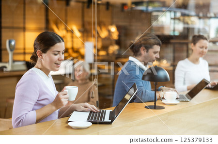 Woman spending time in cozy coffeehouse with laptop and coffee Woman spending time in cozy coffeehouse with laptop and coffee 125379133