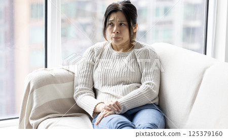 woman feeling sad and tried and sit on the coach, lying on sofa 125379160