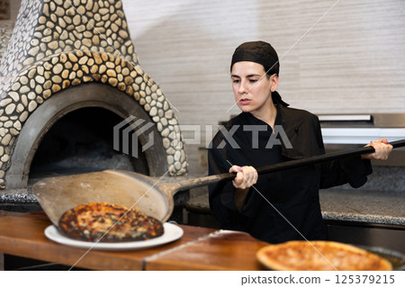 Woman pizza chef at work in restaurant Woman pizza chef at work in restaurant 125379215