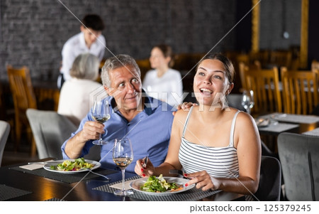 Elderly man resting in restaurant with young female companion 125379245