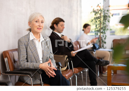 Elderly woman in suit sitting on chair in office 125379255