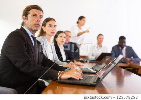 Middle aged white brunette businessman listening to presentation Middle aged white brunette businessman listening to presentation 125379258