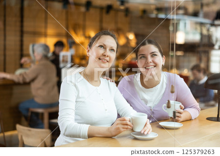 Smiling young female friends drinking coffee at cafe Smiling young female friends drinking coffee at cafe 125379263