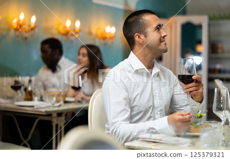 Man with wineglass at the restaurant 125379321