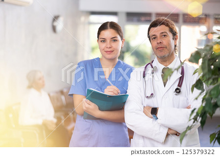 Experienced doctor standing with young female assistant Experienced doctor standing with young female assistant 125379322