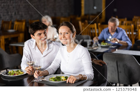 Young guy spending time with adult woman in restaurant Young guy spending time with adult woman in restaurant 125379348