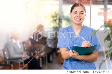 Young female doctor filling clipboard with medical records Young female doctor filling clipboard with medical records 125379385