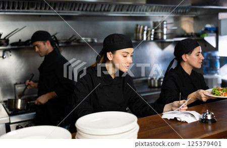 Chef checking orders and giving out salad 125379401