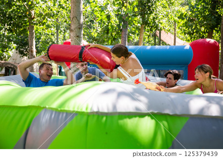 Girl guarding toy chickens fighting off friends with inflatable log 125379439