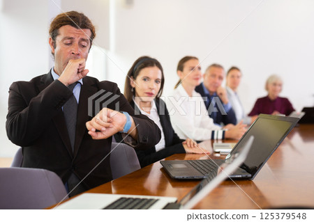Sleepy businessman yawning during conference 125379548