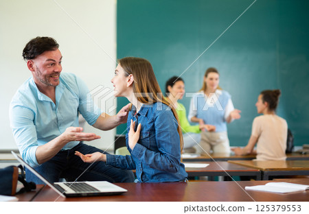Man and woman students having small talk in classroom 125379553