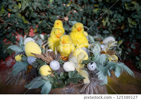 Easter nest with yellow chicks, speckled eggs, and feathers on natural background Easter nest with yellow chicks, speckled eggs, and feathers on natural background 125380127