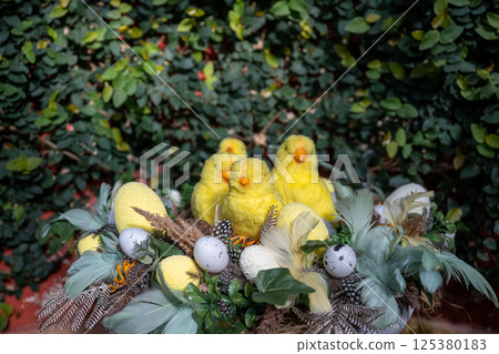 Easter nest with yellow chicks, speckled eggs, and feathers on natural background 125380183