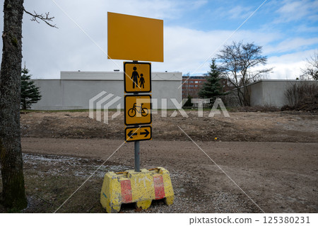 Yellow pedestrian and bicycle path direction sign on a dirt trail at construction site Yellow pedestrian and bicycle path direction sign on a dirt trail at construction site 125380231