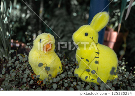 Easter yellow chick and bunny figure in garden foliage during springtime Easter scene  125380254