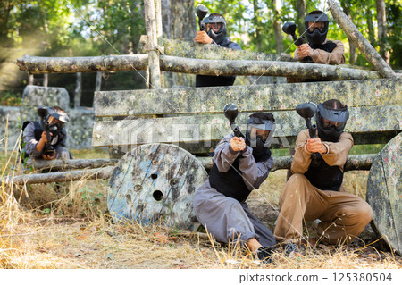 Group of men and women shooting with paintball markers 125380504