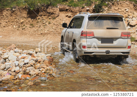 Driving offroad car passing the rocky river on high elevation mountains Driving offroad car passing the rocky river on high elevation mountains 125380721