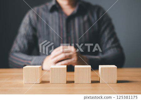 hand of a businessman hold wood empty four blocks with copy space for text or symbols, development concept for growth success process. hand of a businessman hold wood empty four blocks with copy space for text or symbols, development concept for growth success process. 125381175