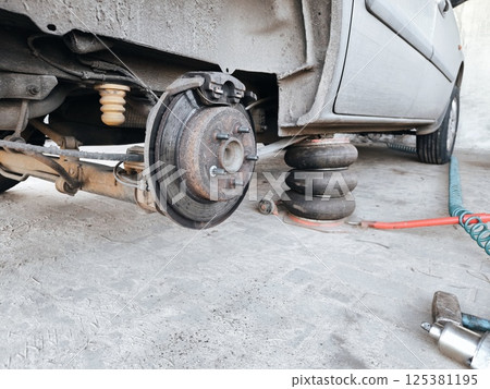 Mechanic at service station checks the brake and steering systems. car wheel maintenance. Mechanic at service station checks the brake and steering systems. car wheel maintenance. 125381195
