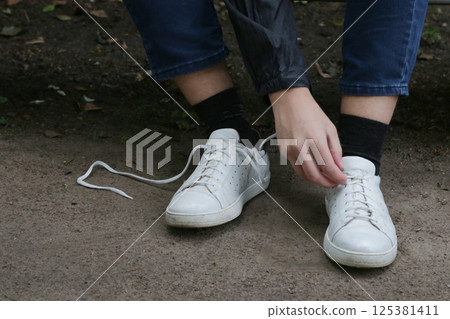 The process of tying shoelaces on sneakers. 125381411