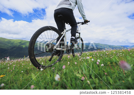 Riding mountain bike on flowering grassland mountain top 125381458