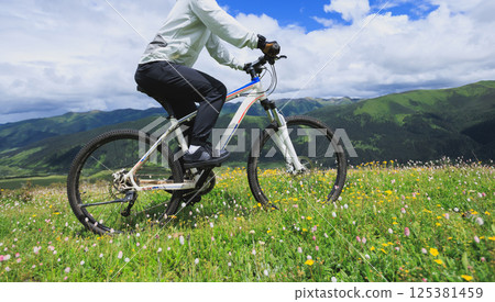 Riding mountain bike on flowering grassland mountain top Riding mountain bike on flowering grassland mountain top 125381459