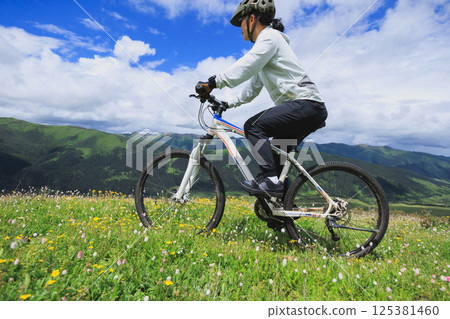 Riding mountain bike on flowering grassland mountain top 125381460