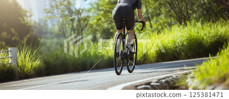 Woman cycling on summer park trail 125381471