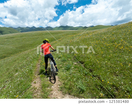 Aerial view of riding mountain bike on flowering grassland mountain Aerial view of riding mountain bike on flowering grassland mountain 125381480