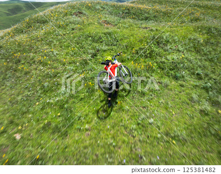 woman carrying mountain bike on beautiful flowering grassland mountain top 125381482